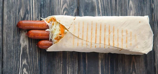 smoked sausage in pita bread on a dark wooden background.photo with copy space