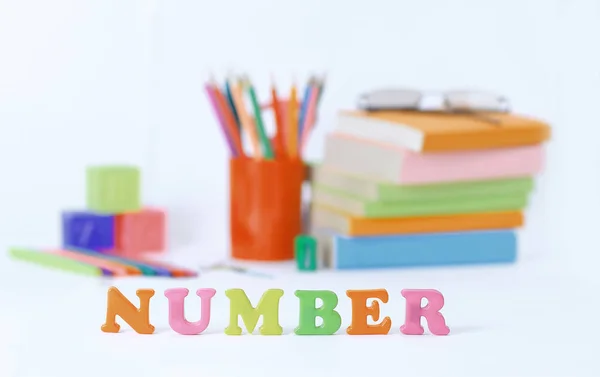 Word number on blurred background of school supplies .photo with copy space — Stock Photo, Image