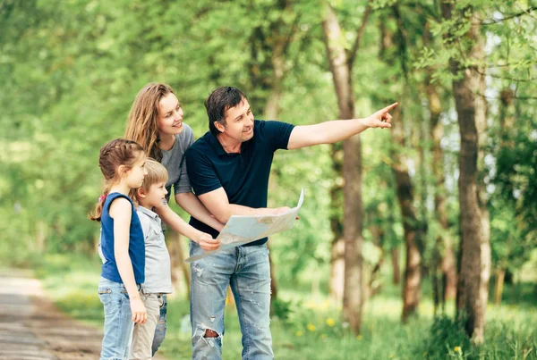 Glückliche Familie schaut auf Landkarten, während sie im Park unterwegs ist — Stockfoto