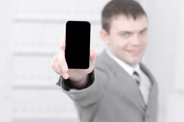 Mann zeigt Bildschirm des Smartphones, während er im Büro steht. — Stockfoto