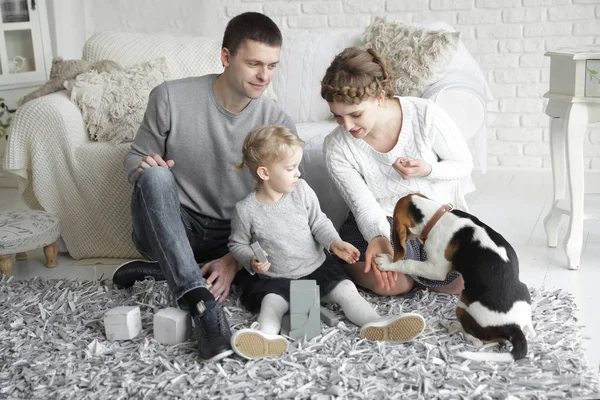 Padres con una hija pequeña y una mascota sentadas en el sofá . — Foto de Stock