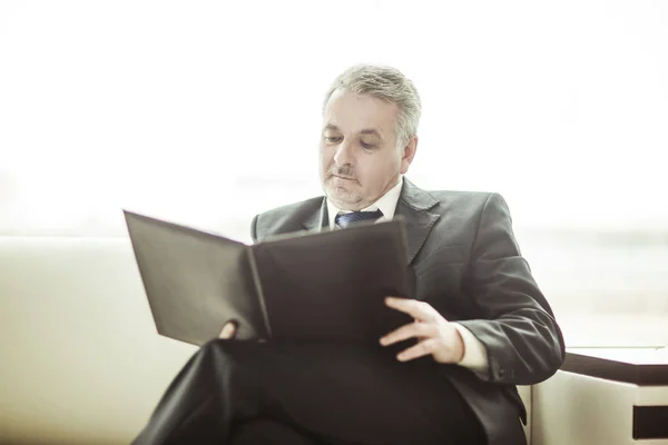 Successful businessman studies working papers sitting on the sofa in the private office — Stock Photo, Image