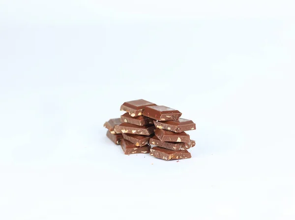 Кусочки тёмного шоколада с орехами, изолированными на белом. — стоковое фото