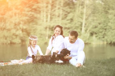 Güneşli bir yaz gününde piknikte köpekli mutlu bir aile. pregn