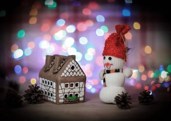 Speelgoed sneeuwpop en peperkoek huis aan de kersttafel — Stockfoto