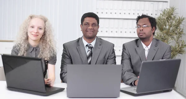 Employees sitting in front of open laptops. isolated on white — Stock Photo, Image