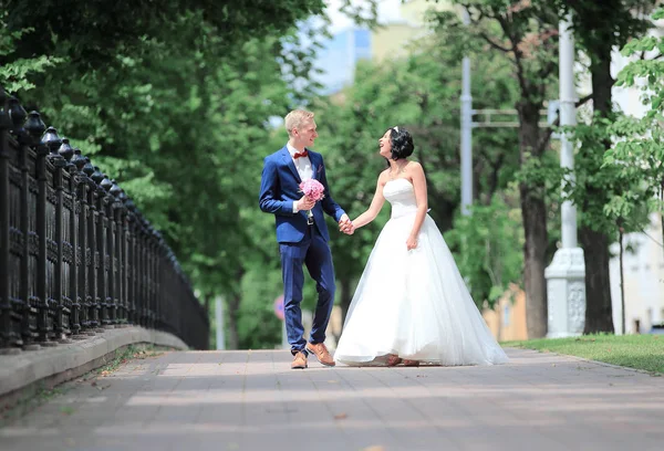 Mladá, krásná nevěsta a ženich procházky po ulici ve městě. — Stock fotografie