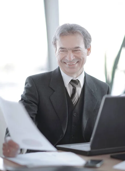 Lachende senior zakenman zit aan zijn Bureau — Stockfoto