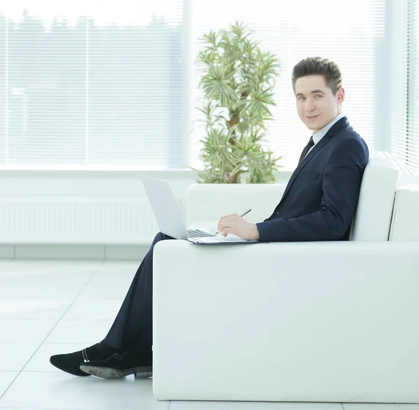 Young businessman working on laptop sitting in the lobby of the — Stock Photo, Image