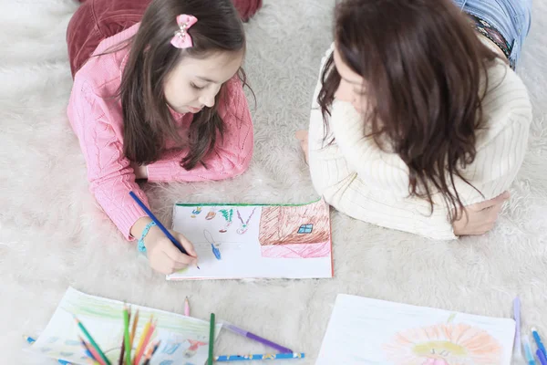Мама і дочка малюють картину, що лежить на підлозі — стокове фото