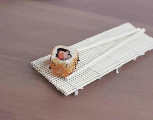 Ätpinnar på trä bakgrund och sushi rullar. — Stockfoto