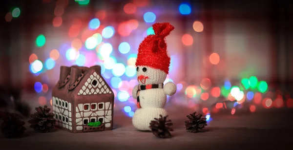 Speelgoed sneeuwpop en peperkoek huis aan de kersttafel — Stockfoto