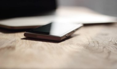 yakın çekim. bulanık görüntü bir cep telefonu ve masanın üstünde laptop
