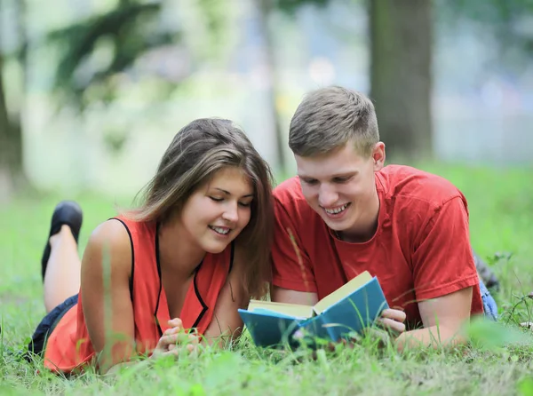 公園の芝生の上に横たわって本を読んで学生のカップル — ストック写真