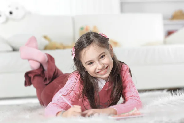 Aus nächster Nähe. Kleines Mädchen zeichnet auf dem Boden liegend im Zimmer — Stockfoto