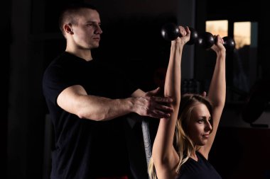 Fitness Eğitmeni kadın müşteri nasıl doğru egzersiz üzerinde simülatörü gerçekleştirileceğini gösterir.