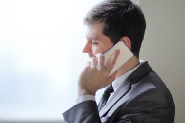 Smartphone cep telefonu ile bir ofis pencere yanında dururken konuşmaya up.businessman kapatın