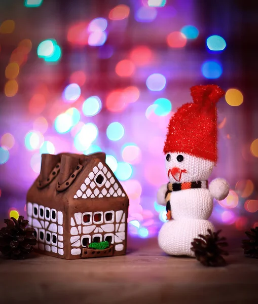 Muñeco de nieve de juguete y casa de jengibre en la mesa de Navidad —  Fotos de Stock