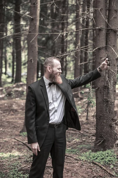 Улыбающийся бизнесмен делает селфи на фоне соснового леса . — стоковое фото