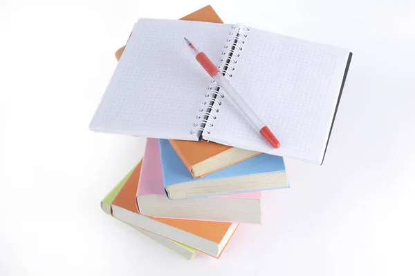 Otwórz Notatnik, długopis i stos książek na białym tle — Zdjęcie stockowe