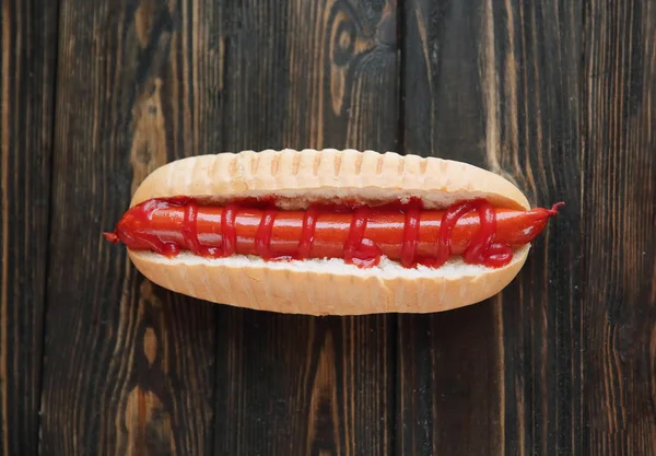 Hot dog con salsiccia affumicata su sfondo di legno scuro.foto con — Foto Stock