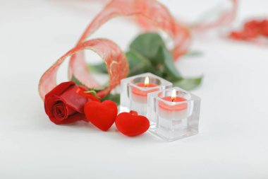 Beyaz arka planda iki mum ve güzel bir gül.