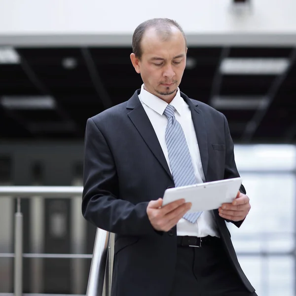 Бизнесмен с цифровым планшетом стоит на офисной лестнице — стоковое фото
