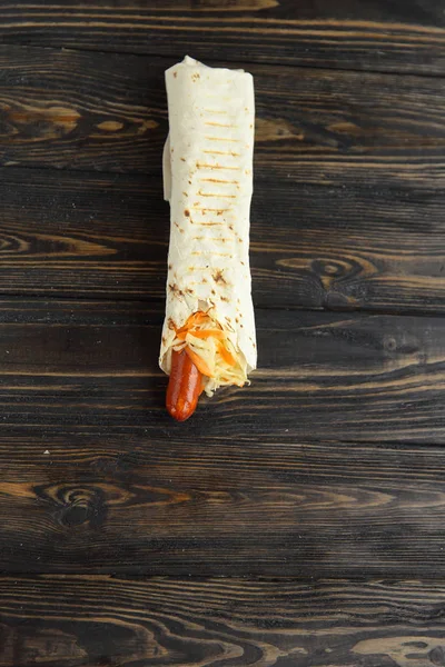 sausage and lettuce wrapped in pita bread on wooden background.photo with copy space