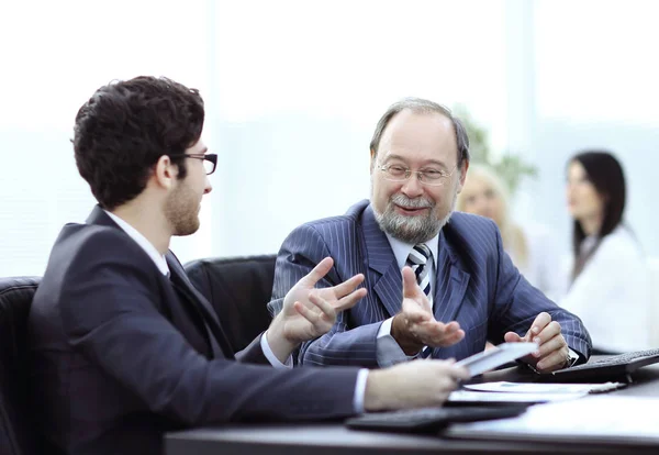 Dos hombres de negocios discutiendo temas de trabajo sentados en su escritorio — Foto de Stock