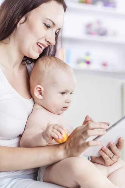 Gelukkig moeder tonen van zijn jaar-oude baby foto's op digitale tablet — Stockfoto