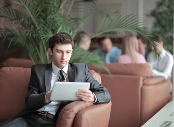 Крупный план молодого бизнесмена с помощью цифрового планшета, сидящего в фойе банка — стоковое фото