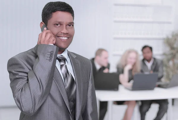 Foreground of a businessman talking on a mobile phone in the office — Stock Photo, Image