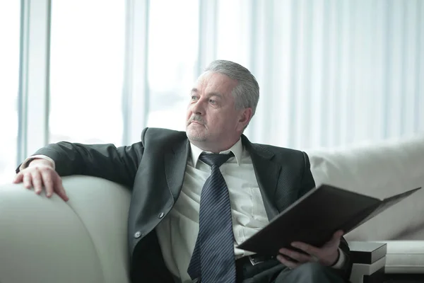 Задумчивый бизнесмен с планшетом сидит на офисном диване — стоковое фото