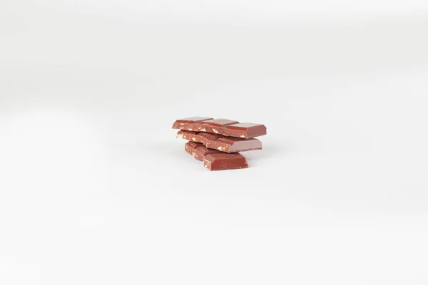 Bitar av mjölkchoklad med nötter isolerad på vit — Stockfoto