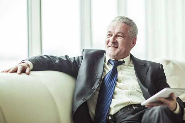 Experienced lawyer with digital tablet sitting on the sofa in the private office — Stock Photo, Image