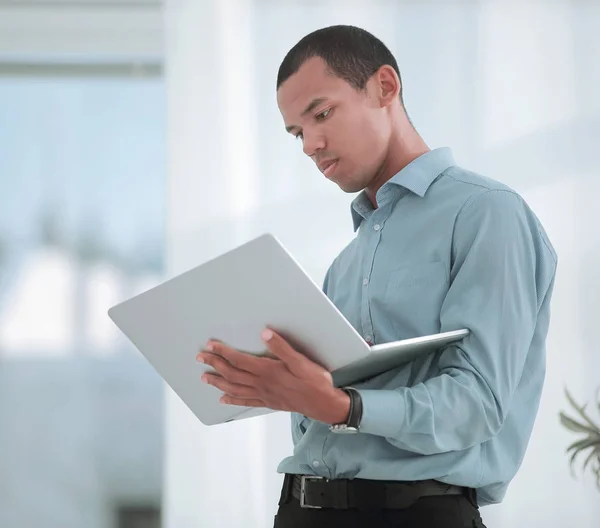 Gestionnaire sérieux travaillant sur un ordinateur portable debout dans le bureau — Photo