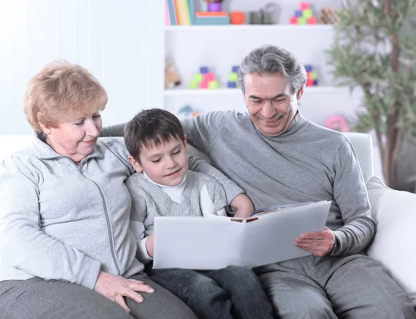 Loving grandparents with grandchild sitting on sofa — Stock Photo, Image