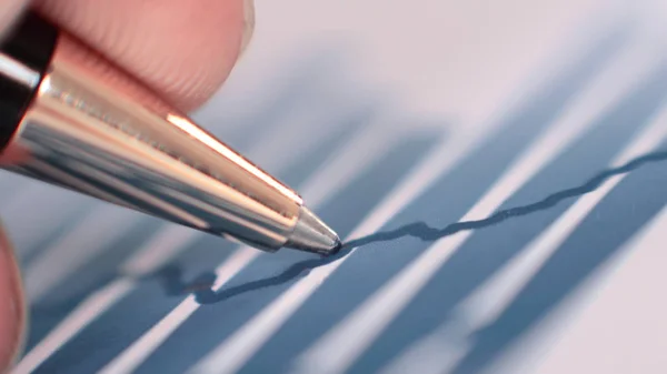 Крупный план бизнес-графов и мужская рука с ручкой — стоковое фото