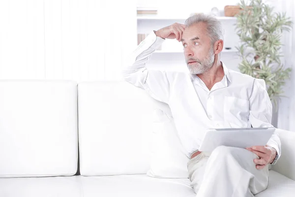 Senior affärsman med digital tablett sitter på soffa — Stockfoto