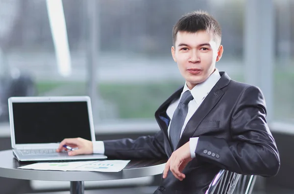 Mladý podnikatel sedí na pracovišti a při pohledu na fotoaparát — Stock fotografie