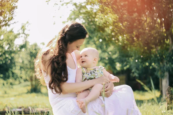 Mom talking to the baby sitting on a bench in the Park — Stock Photo, Image