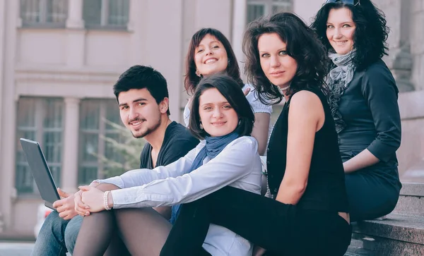 bir grup Univers önünde oturan öğrencinin portresi