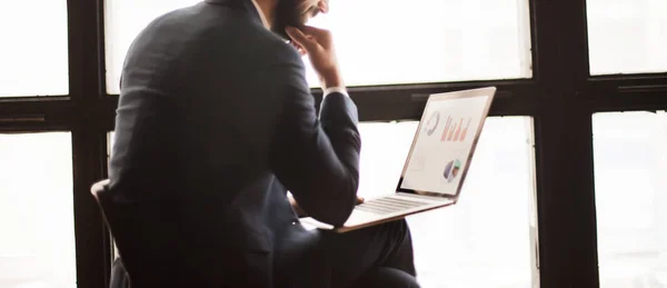 Gerente con un ordenador portátil, trabajando con gráficos financieros cerca de una larg — Foto de Stock