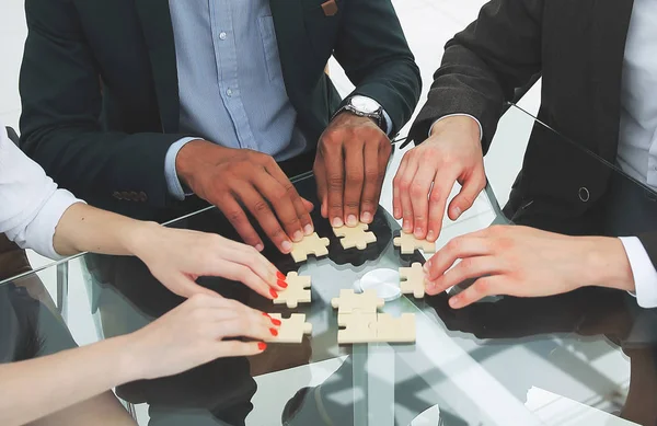 접는 책상 뒤에 앉아 퍼즐의 조각을 하는 성공적인 비즈니스 팀 — 스톡 사진