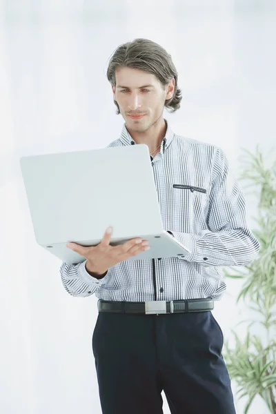 Homme d'affaires sérieux travaillant sur ordinateur portable debout dans le bureau . — Photo