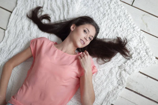 Zavřete up.thoughtful mladá žena ležící na bílý koberec v obývacím pokoji — Stock fotografie