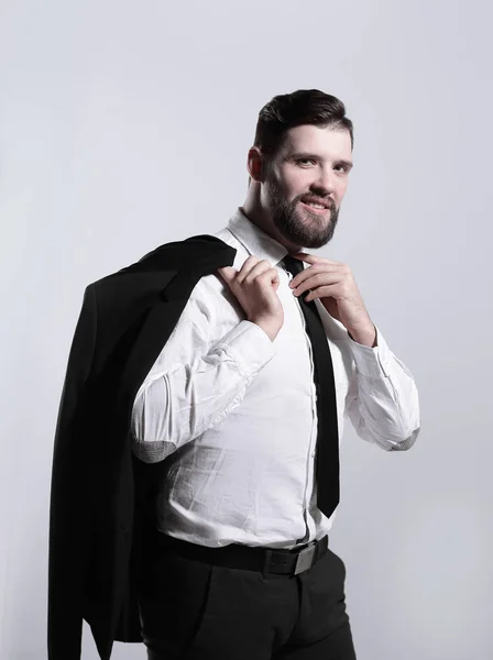 Улыбающийся бизнесмен, держащий пиджак через плечо и выпрямляющий галстук — стоковое фото