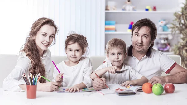 Mamma e papà stanno dipingendo con i bambini seduti a tavola nella nursery — Foto Stock