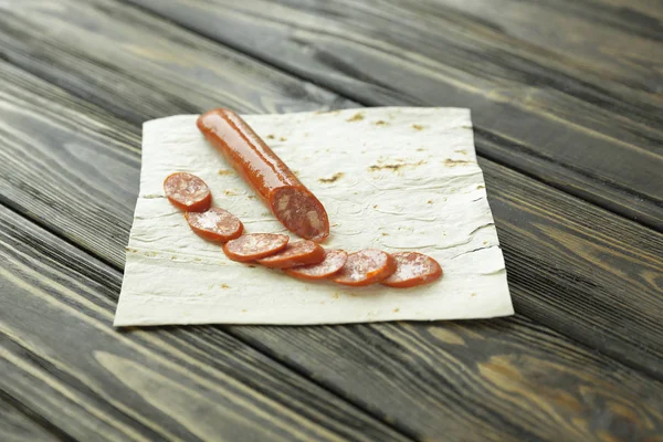 Нарезанный салями на пита-хлебе на деревянном фоне — стоковое фото