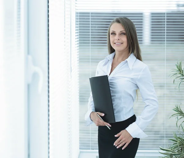 Junge Geschäftsfrau mit Klemmbrett im Hintergrund des Büros. — Stockfoto